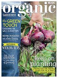 Front cover of Organic Gardener magazine. Issue 115. Close up photograph of a gardeners hands holding a bunch of red onions.